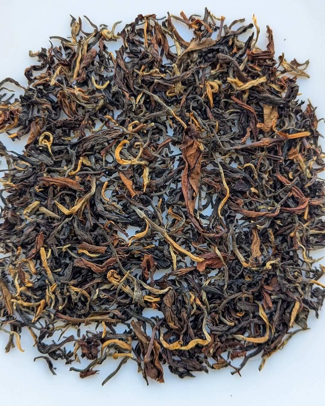 Loose leaf Arunachal Experimental Clonal Gold black tea, showcasing a blend of golden and dark tea leaves.
